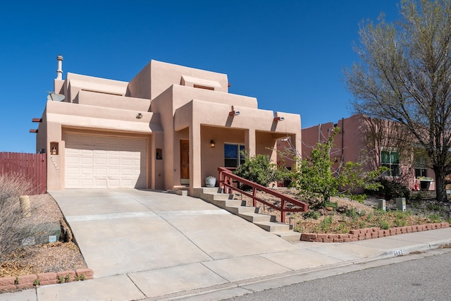 southwest-style home with an attached garage, concrete driveway, stucco siding, and fence