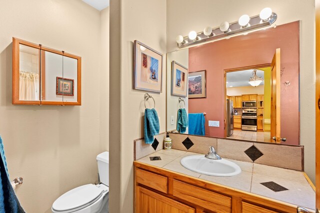 bathroom with backsplash, toilet, and vanity