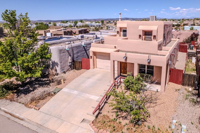 pueblo-style house featuring fence, a balcony, stucco siding, driveway, and a garage