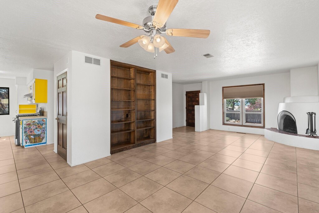 unfurnished living room featuring light tile patterned flooring, a textured ceiling, and visible vents