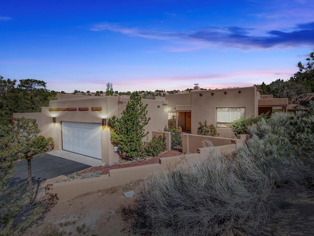 adobe home featuring stucco siding, driveway, and a garage