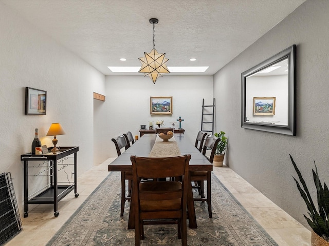 dining space featuring recessed lighting, a textured wall, a textured ceiling, and a skylight
