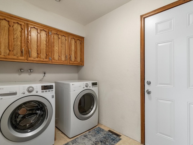laundry room with light tile patterned flooring, washer and dryer, and cabinet space