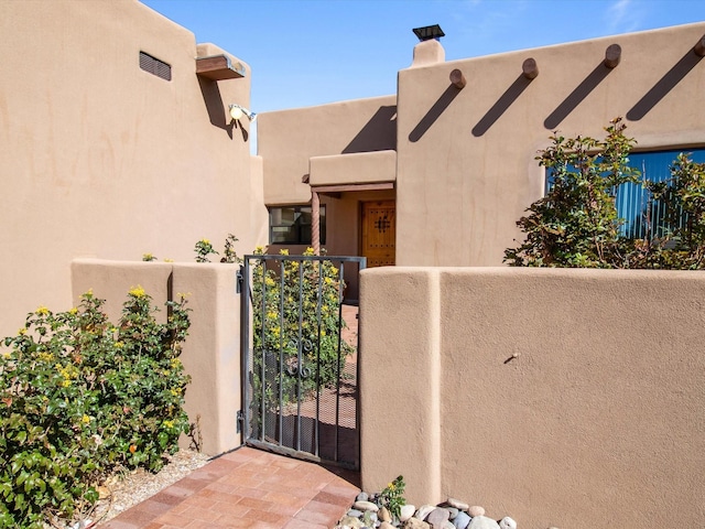 exterior space featuring a gate, fence, and stucco siding