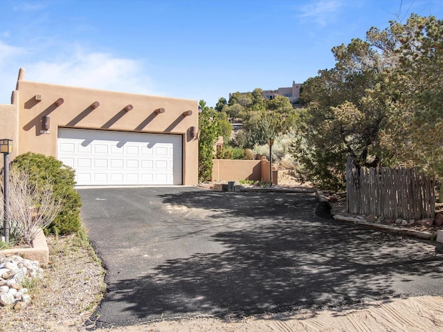 view of home's exterior featuring fence, aphalt driveway, and stucco siding