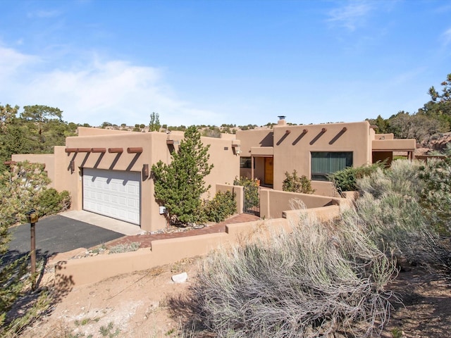 adobe home with an attached garage, driveway, and stucco siding
