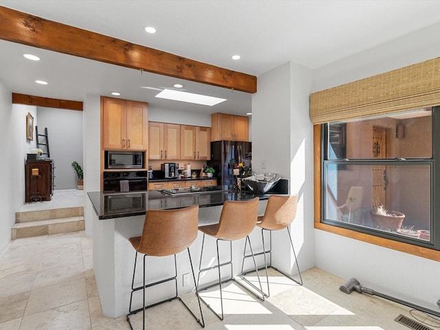 kitchen with dark countertops, black appliances, a breakfast bar area, visible vents, and recessed lighting