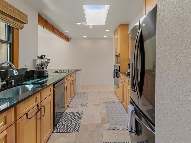 kitchen featuring a sink, dark stone counters, recessed lighting, a skylight, and black appliances