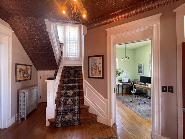 1607 8th St, Las Vegas, NM 87701 - stairs with wood-type flooring, an ornate ceiling, radiator, and a chandelier