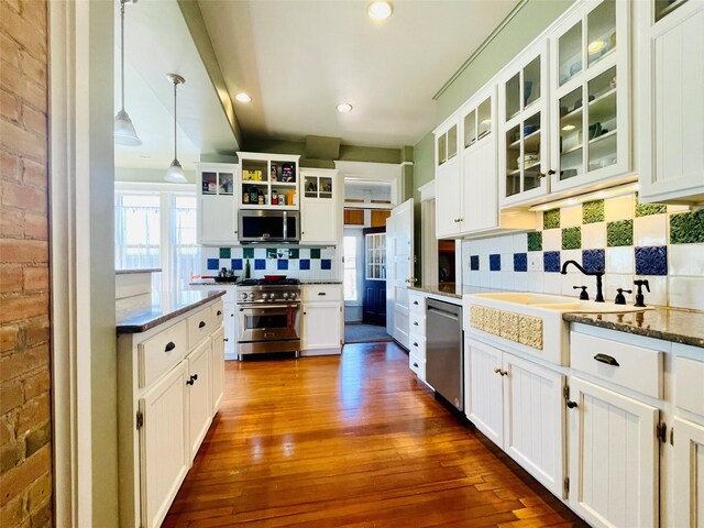 1607 8th St, Las Vegas, NM 87701 - kitchen with decorative backsplash, white cabinetry, decorative light fixtures, appliances with stainless steel finishes, and dark wood-style floors