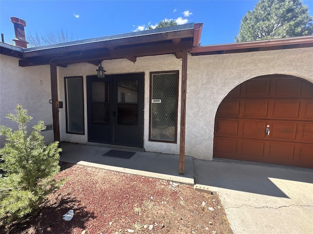 property entrance with an attached garage and stucco siding