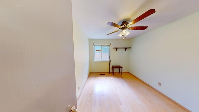 empty room featuring ceiling fan, baseboards, visible vents, and light wood finished floors