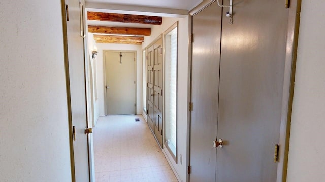 hall with light floors and beamed ceiling