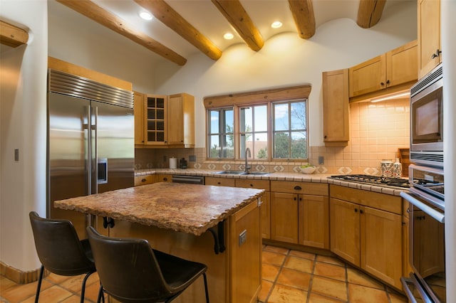 kitchen with a kitchen breakfast bar, beam ceiling, a sink, built in appliances, and a kitchen island