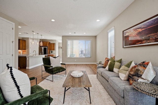 living room featuring light wood finished floors, recessed lighting, and baseboards