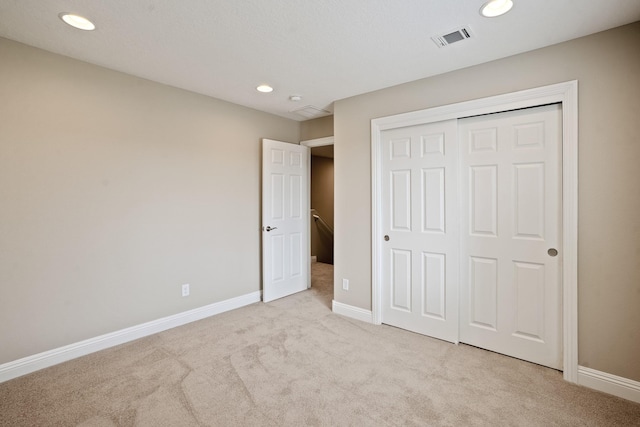 unfurnished bedroom featuring recessed lighting, a closet, carpet, baseboards, and visible vents