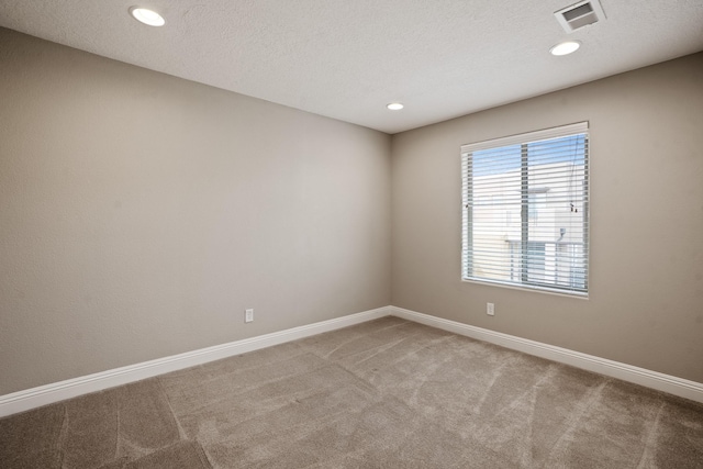 carpeted empty room with a textured ceiling, visible vents, recessed lighting, and baseboards