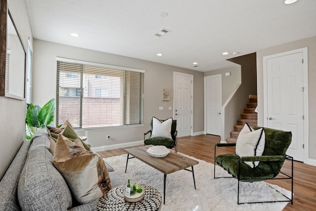 living room with baseboards, visible vents, stairway, and light wood-type flooring