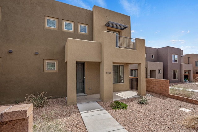 adobe home featuring stucco siding and a balcony