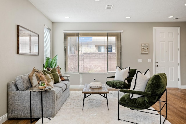 living room featuring baseboards, visible vents, wood finished floors, and recessed lighting