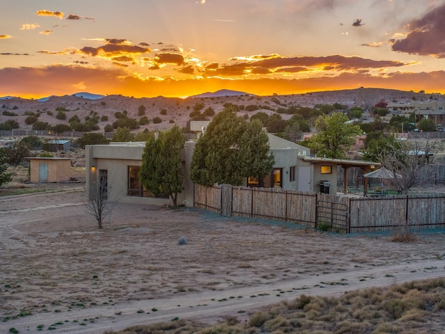 back of property with stucco siding, a mountain view, and fence private yard