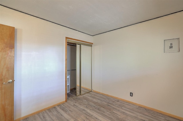 unfurnished bedroom with light wood-type flooring, a closet, and baseboards