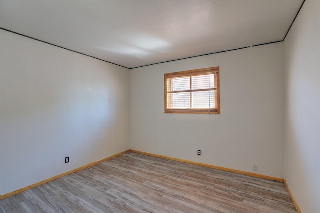 spare room featuring light wood-style flooring and baseboards