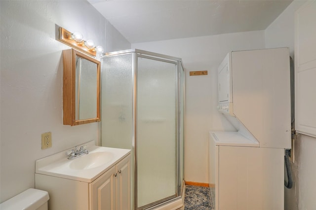 bathroom with stacked washer and clothes dryer, a shower stall, toilet, and vanity