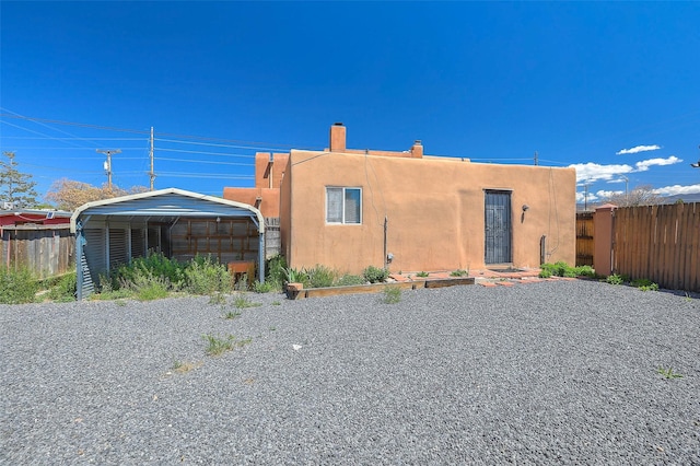 exterior space with fence, a chimney, a carport, and stucco siding