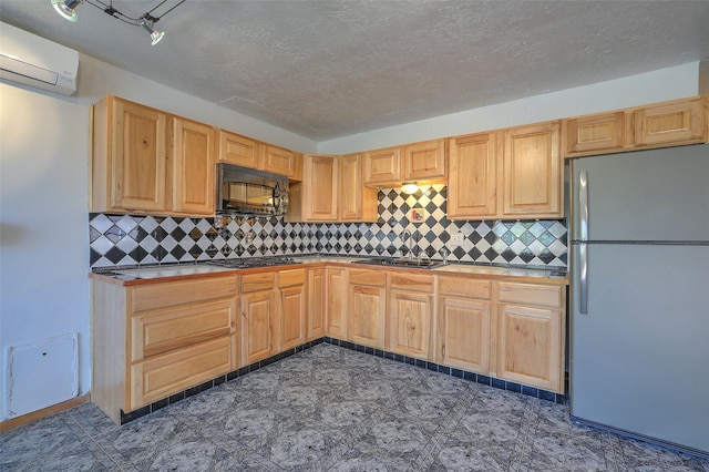 kitchen featuring black microwave, a wall mounted AC, freestanding refrigerator, and backsplash