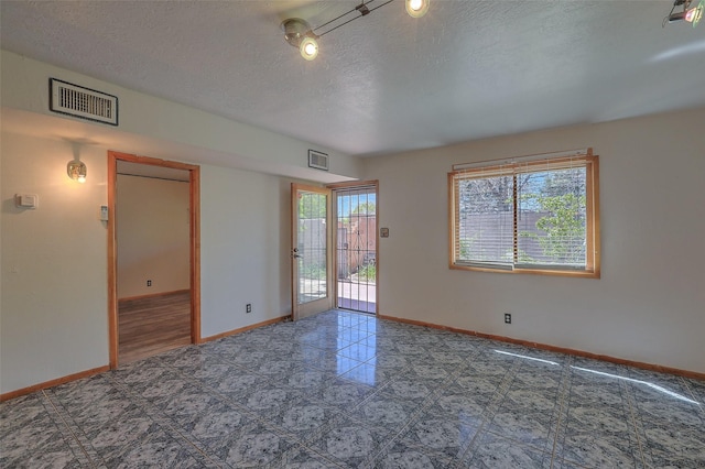 empty room featuring a textured ceiling, visible vents, and baseboards