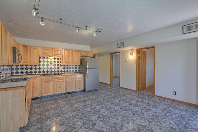 kitchen with appliances with stainless steel finishes, visible vents, tasteful backsplash, and light brown cabinetry