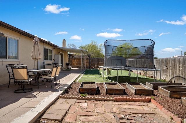 2416 Avenida De Las Campanas, Santa Fe, NM 87507 - view of patio featuring a trampoline, a vegetable garden, and outdoor dining space