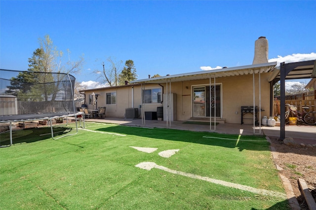 2416 Avenida De Las Campanas, Santa Fe, NM 87507 - back of house featuring a trampoline, a patio, central air condition unit, stucco siding, and a chimney
