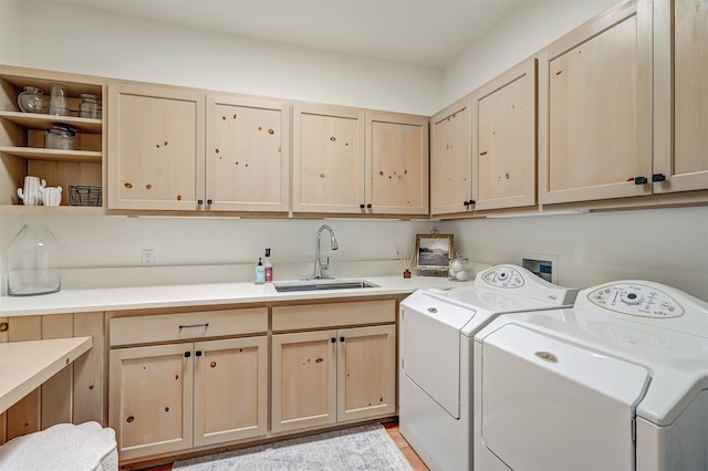 clothes washing area with separate washer and dryer, a sink, and cabinet space
