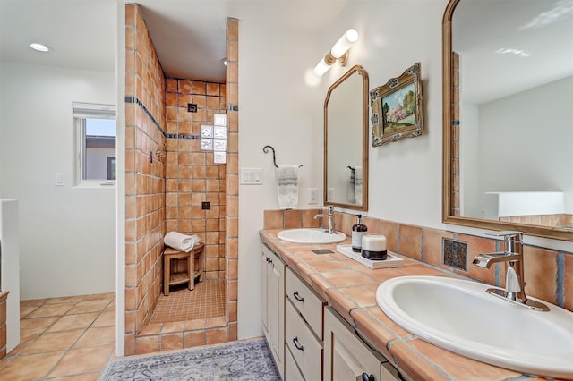 full bathroom with double vanity, a tile shower, and a sink