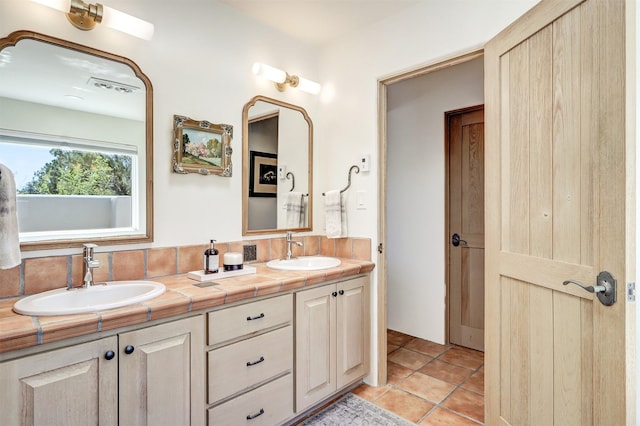 full bath featuring double vanity, visible vents, tile patterned floors, and a sink