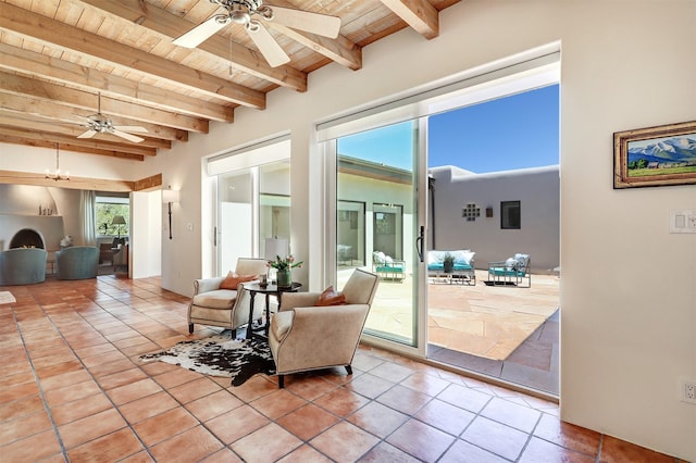 living area with beamed ceiling, a ceiling fan, wooden ceiling, and tile patterned flooring