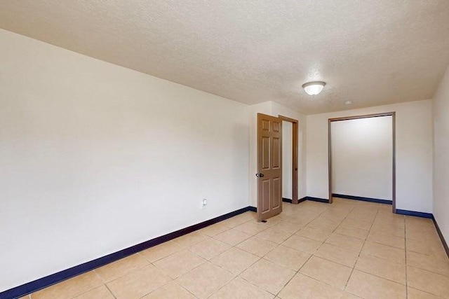 spare room with a textured ceiling and baseboards