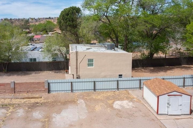 exterior space with an outdoor structure, cooling unit, a storage unit, stucco siding, and fence