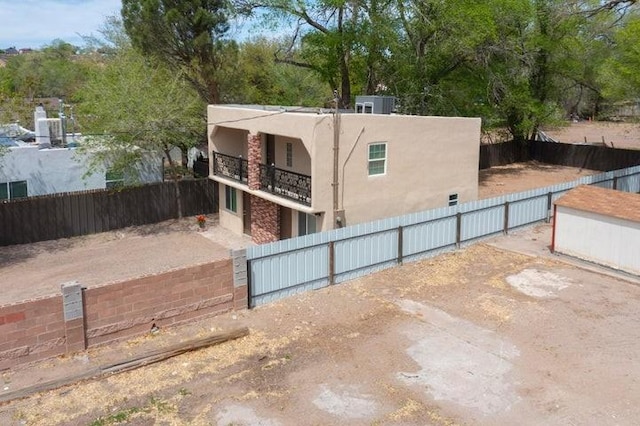 exterior space with stucco siding, a balcony, and a fenced front yard