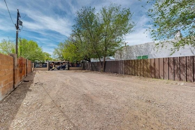 view of street with a gate, dirt driveway, and a gated entry