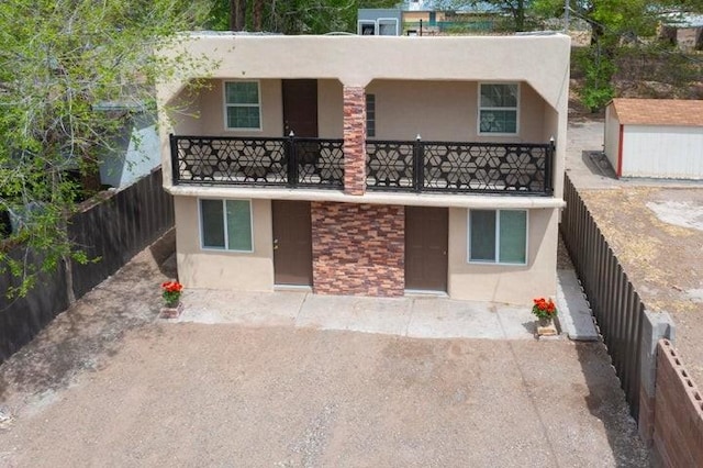 rear view of property featuring stucco siding, a balcony, a patio, and a fenced backyard