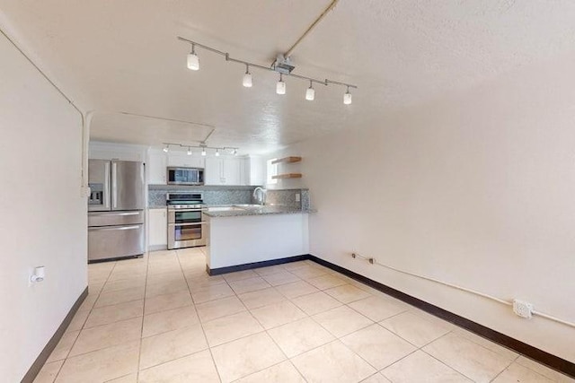 kitchen with stainless steel appliances, light tile patterned floors, rail lighting, a peninsula, and white cabinets