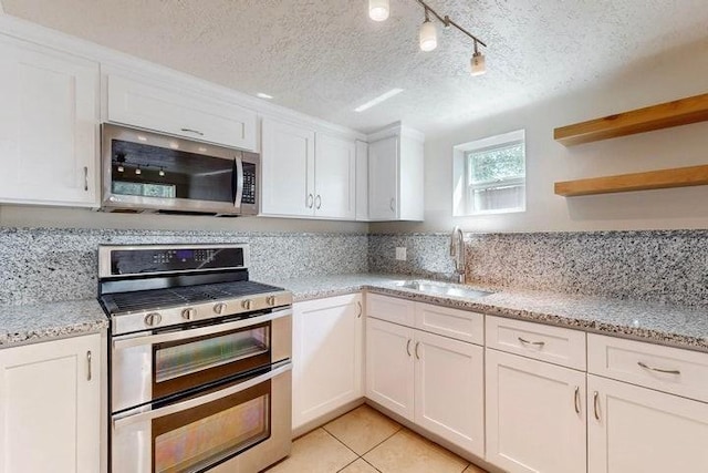 kitchen featuring a textured ceiling, a sink, white cabinetry, and stainless steel appliances