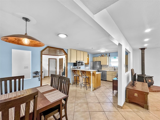 dining space with recessed lighting, light tile patterned floors, and a wood stove