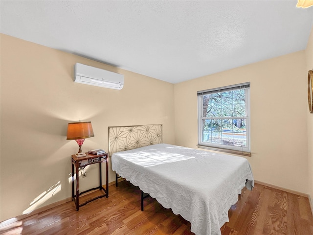 bedroom featuring an AC wall unit, baseboards, and wood finished floors