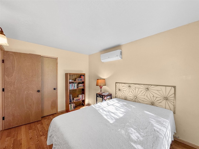 bedroom with an AC wall unit, wood finished floors, and a closet