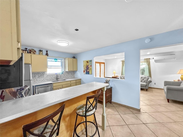 kitchen with light countertops, cream cabinetry, appliances with stainless steel finishes, and a sink