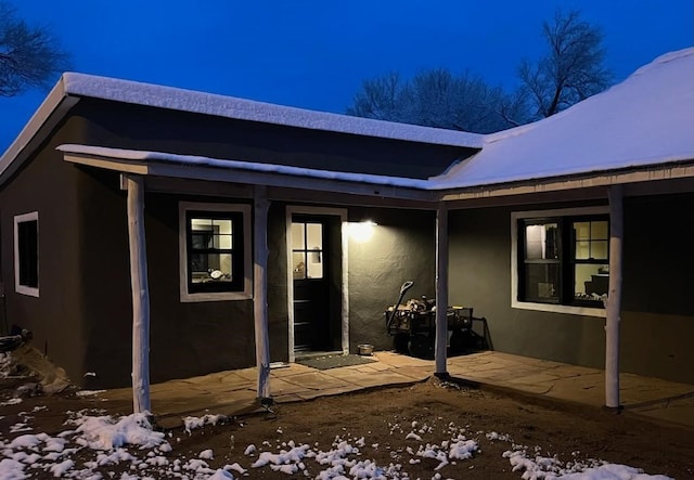 54 County Road B40A, Ribera, NM 87560 - snow covered property entrance with stucco siding and a patio